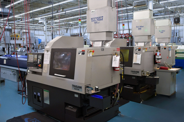 Tsugami S206 CNC Swiss-type lathe operating on a manufacturing floor with integrated mist collection system and control panel visible